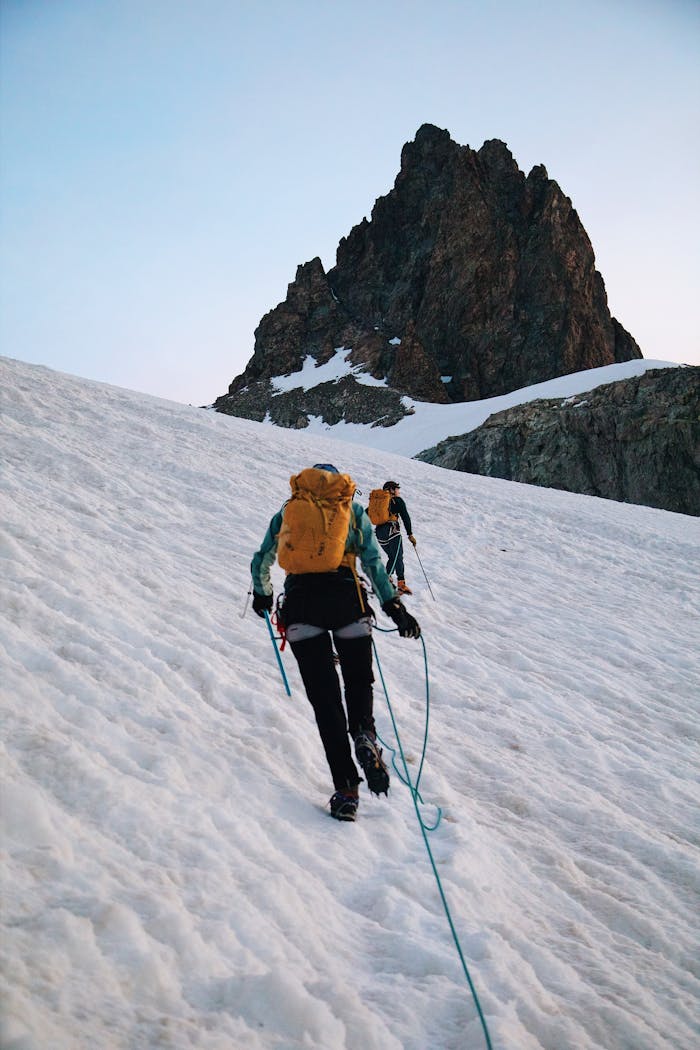 Two people climbing up a snowy mountain